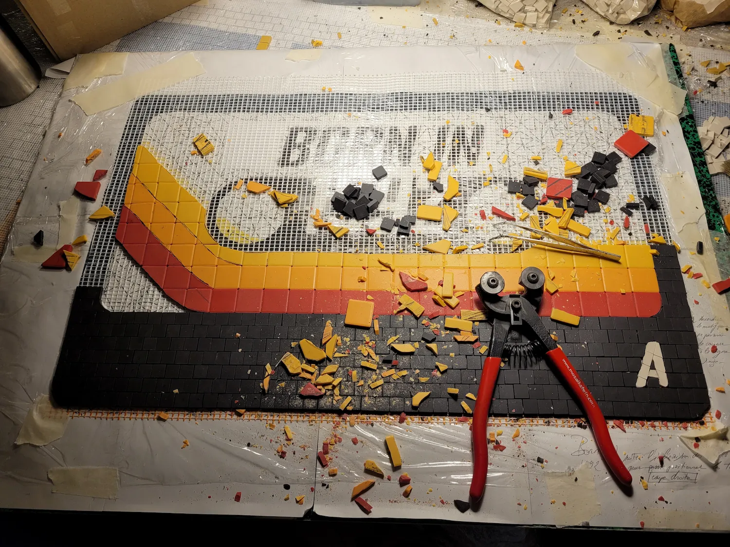 Zoom sur éclats de mosaïques noir, jaune et rouge